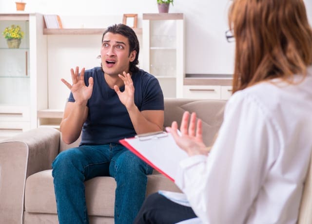 Young male patient discussing with female psychologist